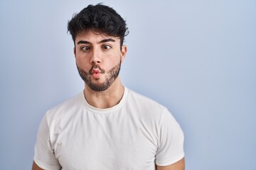 Obraz premium Hispanic man with beard standing over white background making fish face with lips, crazy and comical gesture. funny expression.