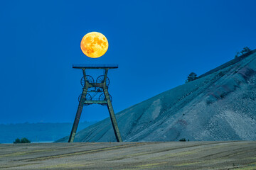 Naklejka premium The moon above the winding tower at the spoil tip