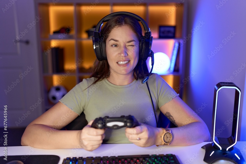 Canvas Prints beautiful brunette woman playing video games wearing headphones winking looking at the camera with s