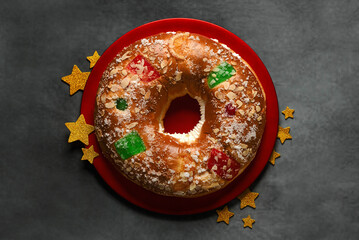 Top view of Roscon de reyes on a red plate with golden stars. Kings day concept spanish three kings cake