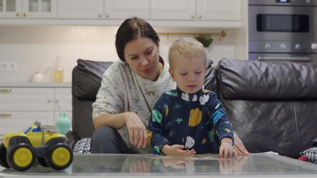 mother and toddler child little boy solving a jigsaw puzzle for kids at home