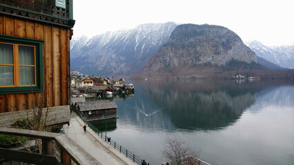 Serene Hallstatt village in March, with the tranquil lake mirroring the sleepy, snow-capped mountains. Idyllic off-season tranquility, showcasing quiet streets and majestic Alpine backdrop.