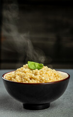 cooked ptitim pasta in a bowl with hot steam, vertical image. copy space for text