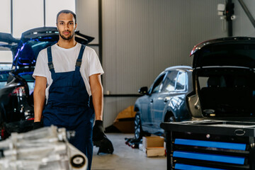 Portrait of experienced successful auto mechanic in workplace checking the condition of the car in automobile repair maintenance station garage.