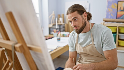 Young hispanic man artist drawing at art studio