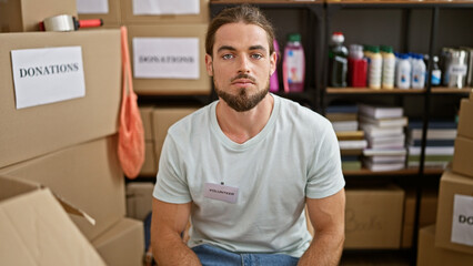 Young hispanic man volunteer sitting with relaxed face at charity center