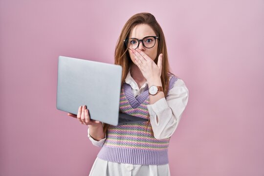 Young caucasian woman working using computer laptop shocked covering mouth with hands for mistake. secret concept.