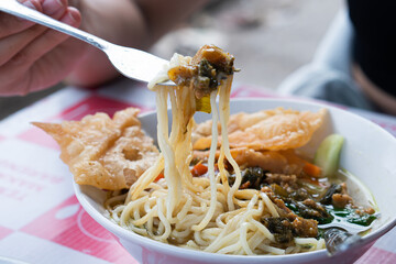 Female pulling noodles out of ramen soup
