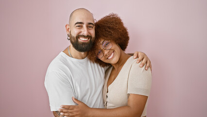 Joyful beautiful couple exuding confidence, enjoying a casual lifestyle, sharing a warm hug and smiling over isolated pink background while laughing and standing together in love