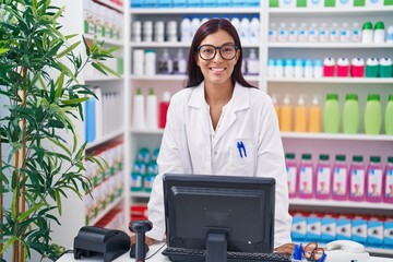 Young beautiful hispanic woman pharmacist smiling confident using computer at pharmacy
