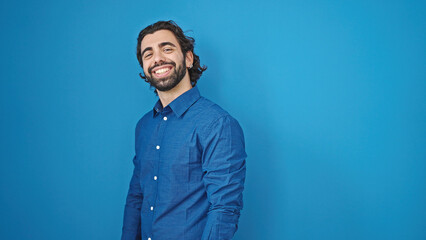 Young hispanic man smiling confident standing over isolated blue background