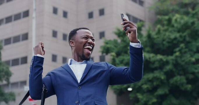 Excited, happy black man on phone, celebrating success receiving positive, good news or work promotion. Business man making yes hand gesture after victory or winning lottery, standing in the city.