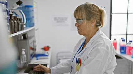 In lab bliss, middle age blonde scientist woman immersed in research, working at computer in...