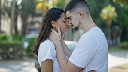 Beautiful, confident couple, smiling and hugging, deeply looking into each other's eyes expressing positive joy, basking in sunlight at the city park. lifestyle of love and happiness outdoors.