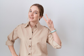 Young caucasian woman wearing casual shirt smiling looking to the camera showing fingers doing...