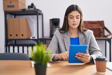Young beautiful hispanic woman business worker using touchpad at office