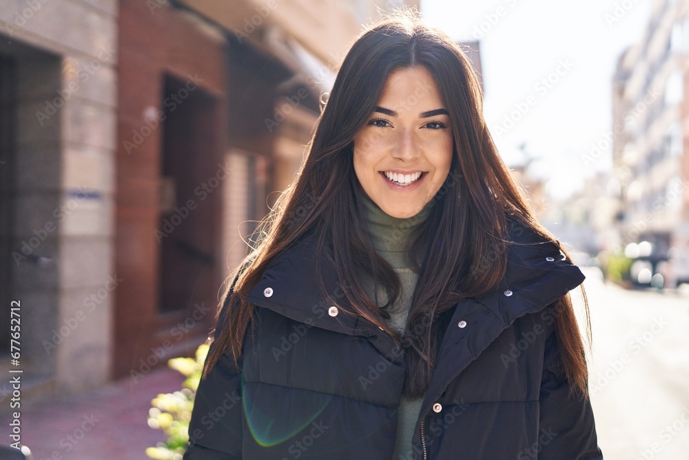 Wall mural Young beautiful hispanic woman smiling confident standing at street