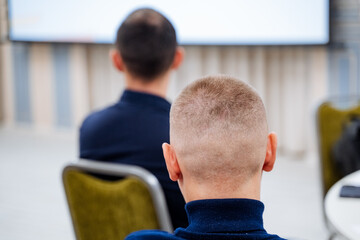 The back of the young man's head is shaved bald, short haircut, back view, top of the head.