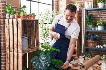 Young hispanic man florist using difusser working at florist