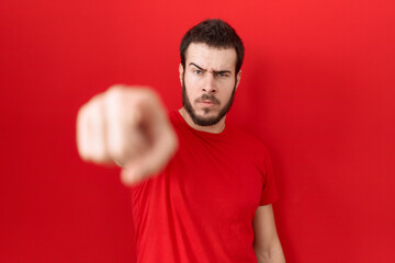 Young hispanic man wearing casual red t shirt pointing displeased and frustrated to the camera, angry and furious with you