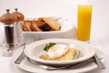 Poached egg on top of smoked haddock on a plate with toast and a glass orange juice