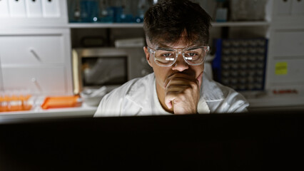 Handsome, serious-faced young hispanic male scientist engrossed in high-stakes research, working...