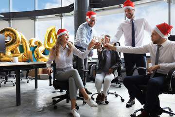 Business people are celebrating holiday in modern office drinking champagne and having fun in...