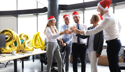 Business people are celebrating holiday in modern office drinking champagne and having fun in...