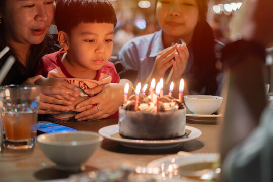 Cropped view of An Asian litte cute boy happy and his family on celebrate birthday with festive cake