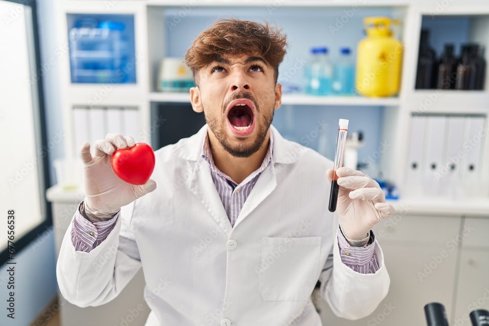 Sticker arab man with beard working at scientist laboratory holding blood samples angry and mad screaming fr