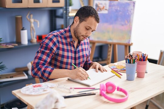 Young man artist drawing on notebook at art studio