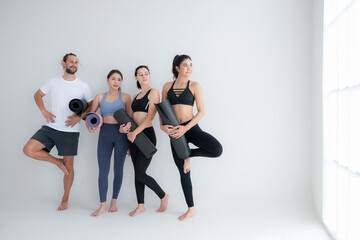 Obraz premium A group of female and male athletes stood and chatted amicably in the studio before beginning with the yoga class.