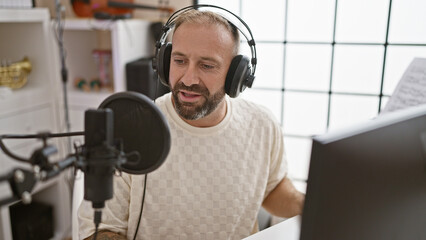 Handsome young man, a smiling reporter wearing headphones, expertly presenting a live radio show...
