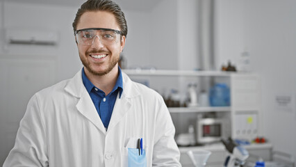 Young hispanic man scientist smiling confident standing at laboratory - obrazy, fototapety, plakaty