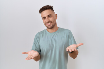 Hispanic man with beard standing over white background smiling cheerful with open arms as friendly welcome, positive and confident greetings