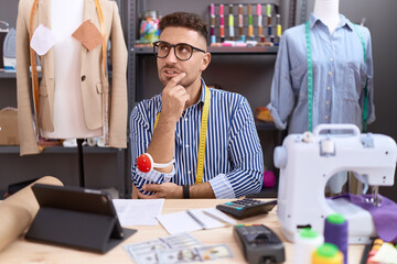 Hispanic man with beard dressmaker designer working at atelier thinking worried about a question, concerned and nervous with hand on chin