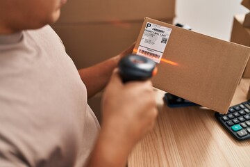 Young latin man ecommerce business worker scanning package at office
