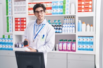 Young hispanic man pharmacist smiling confident scanning pills bottle at pharmacy