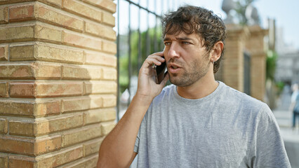 Portrait of a handsome, young guy, with blond beard talking on his phone, deep in concentration....