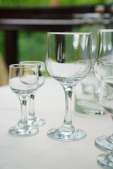 Empty wine glasses and shot glasses on a table with a white tablecloth.
