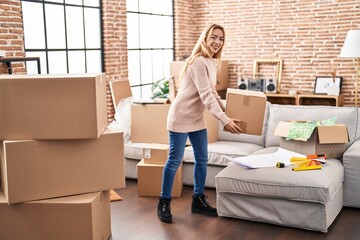 Young woman smiling confident holding package at new home