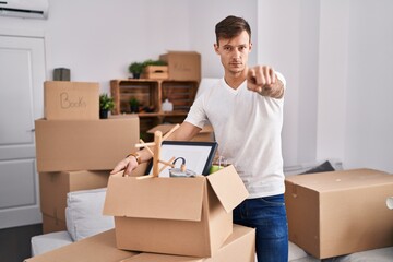 Caucasian man holding screwdriver at new home pointing with finger to the camera and to you, confident gesture looking serious