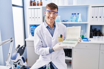Caucasian man working at scientist laboratory smiling with a happy and cool smile on face. showing...
