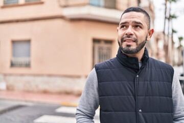 Naklejka premium Young latin man smiling confident looking to the side at street