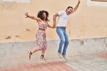 Man and woman couple smiling confident jumping at street