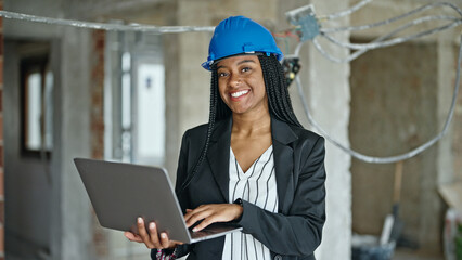 African american woman architect smiling confident using laptop at construction site