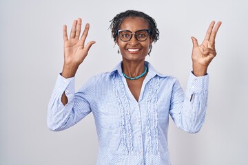 African woman with dreadlocks standing over white background wearing glasses showing and pointing...