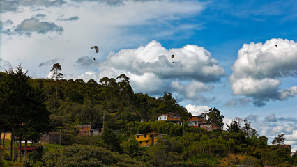 Foto en San Felix, Bello, Colombia. Se aprecia en la foto a personas disfrutando del vuelo en parapente, en un lugar con paisajes extraordinarios. - obrazy, fototapety, plakaty