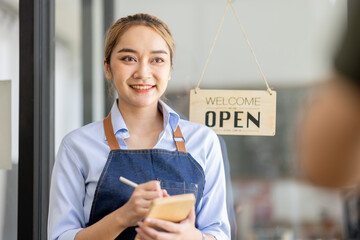 Happy SME business barista cafe owner Asian woman waitress apron and staning at the door with a sign Open waiting for customers , cafes and restaurants entrepreneur Small business concept.