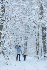 It is a beautiful winter day as the couple walks through the forest. On the shoulder of a man, he...